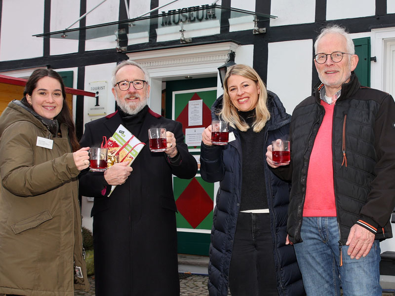 Vier Personen präsentieren gefüllte Glastassen in Richtung Kamera.